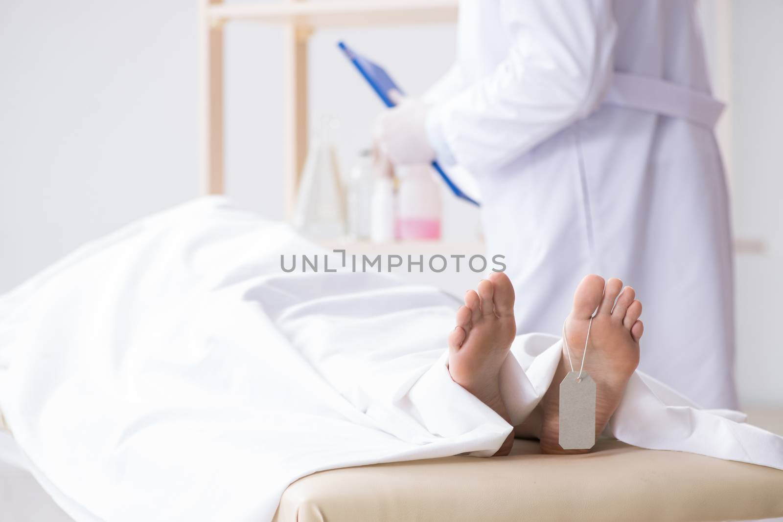 Police coroner examining dead body corpse in morgue