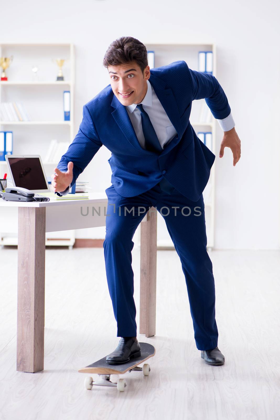 Young businessman with skate in office in sports concept