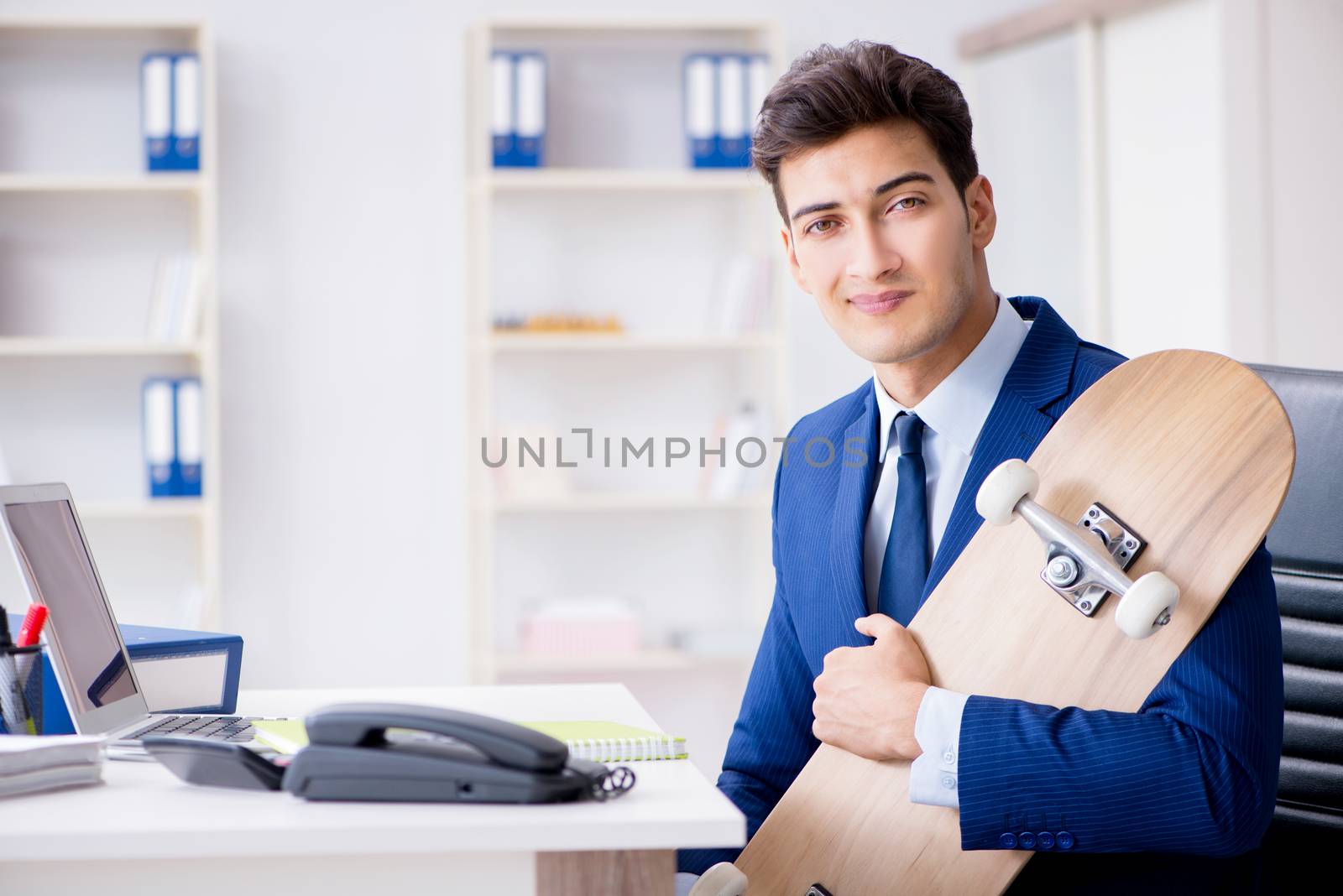 Young businessman with skate in office in sports concept