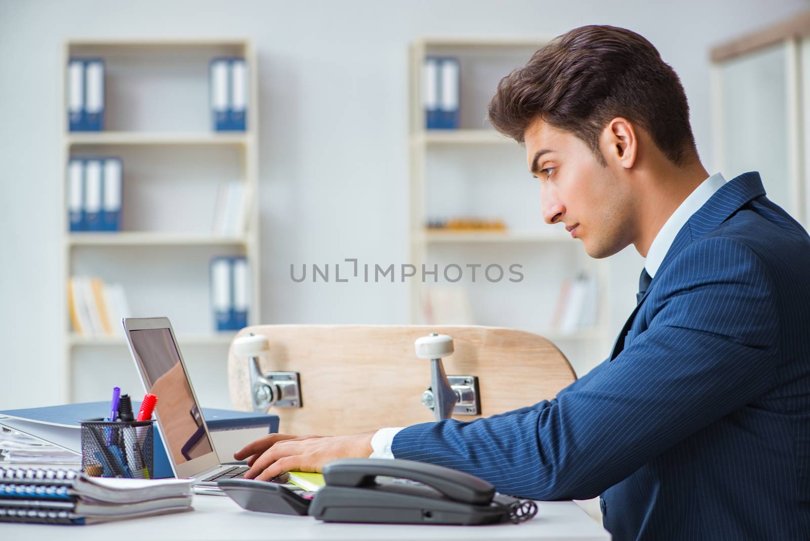 Young businessman with skate in office in sports concept