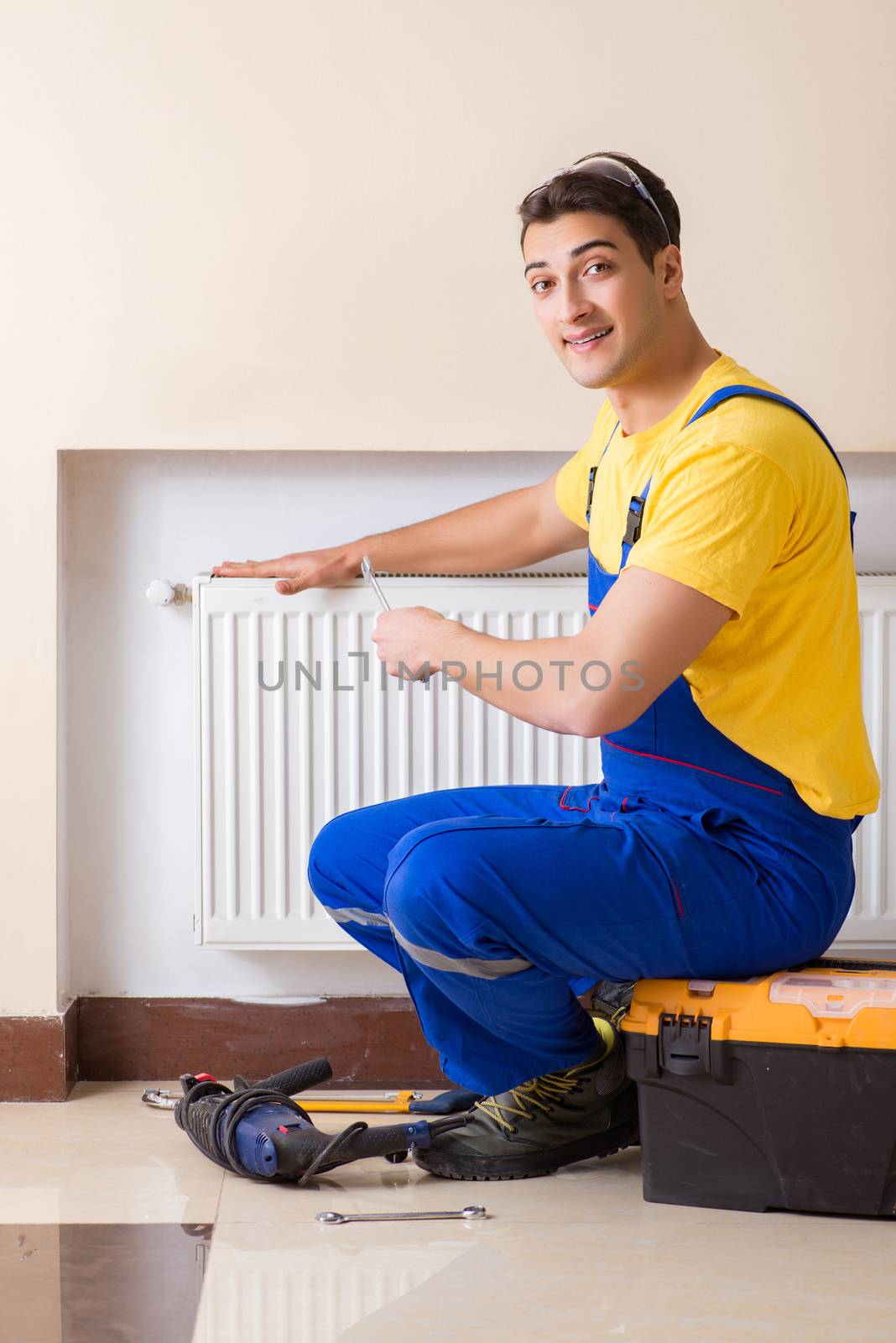 Young repairman contractor repairing heating panel 