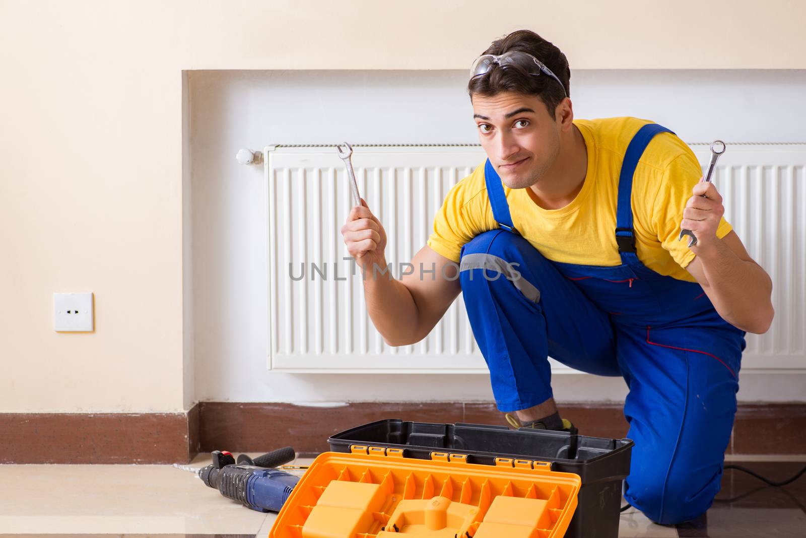 Young repairman contractor repairing heating panel 