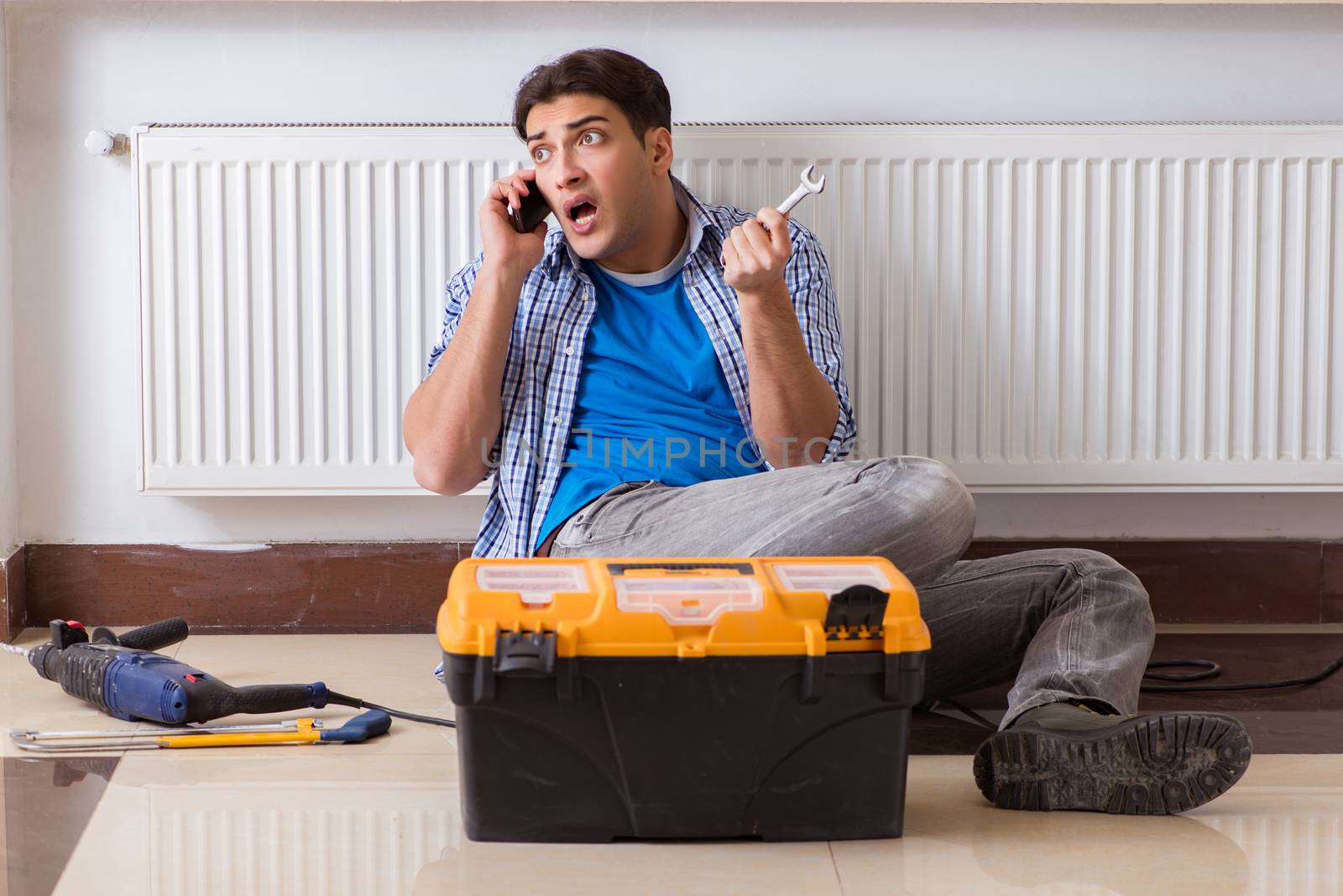 Young repairman contractor repairing heating panel 