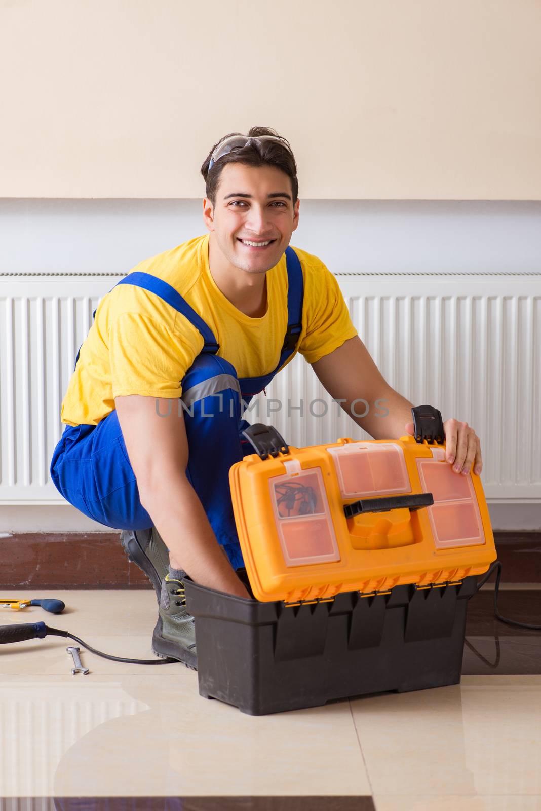 Young repairman contractor repairing heating panel 