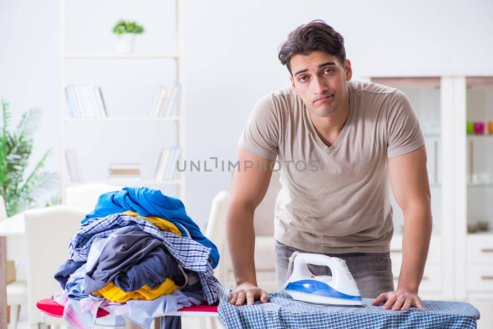 Young man husband doing clothing ironing at home