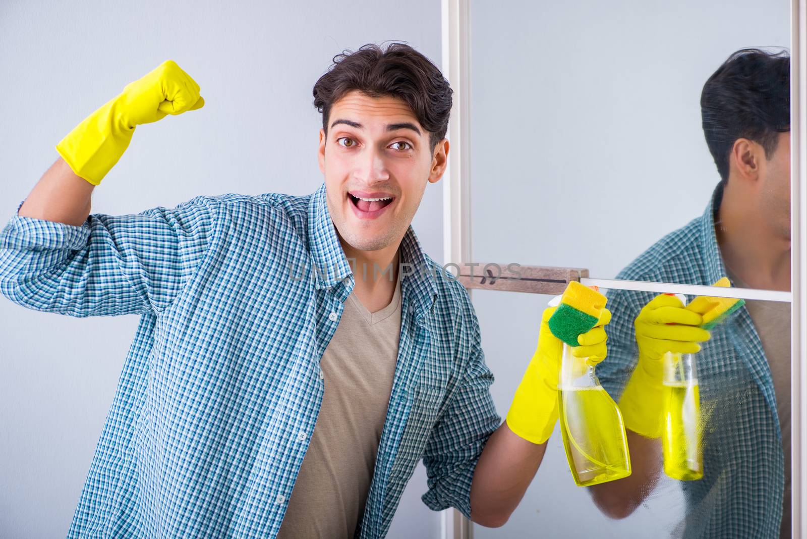 Young man cleaning mirror at home hotel