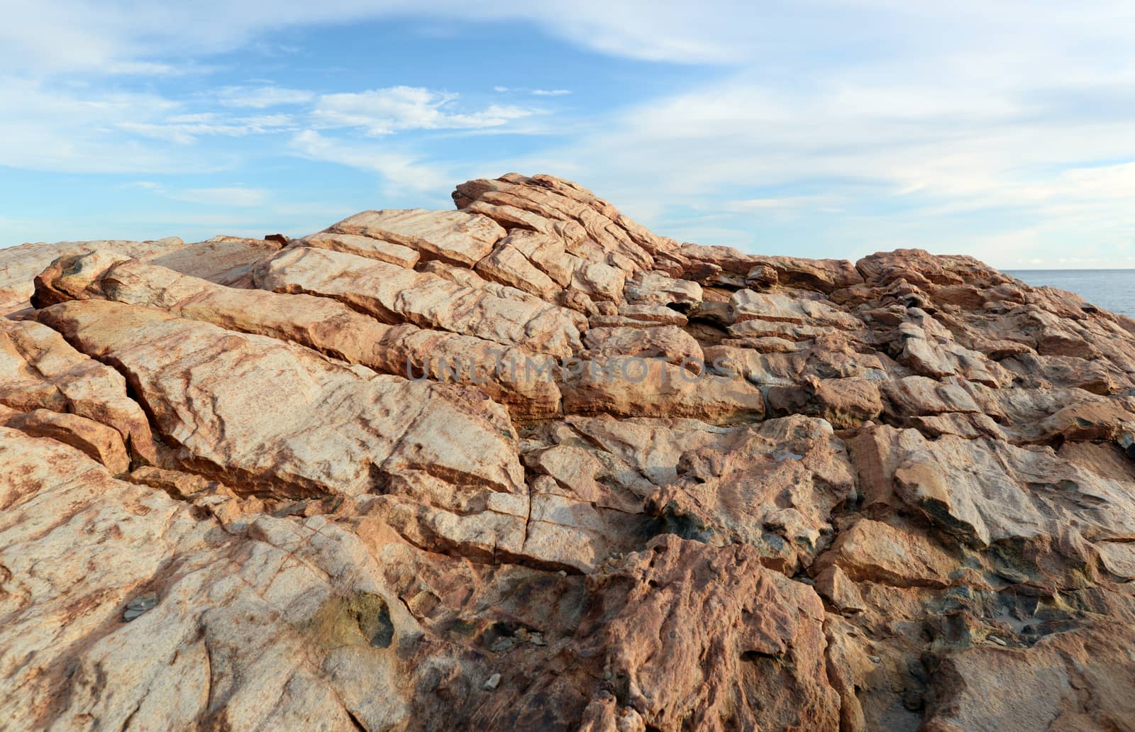 The cracked brown rocks On the background is a bright sky in the afternoon. Located by the sea in the eastern part of Thailand