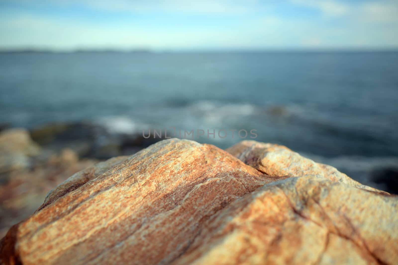 The brown rocks by the sea are on the background of the sea and the blurry sky, Sea in the east of Thailand.