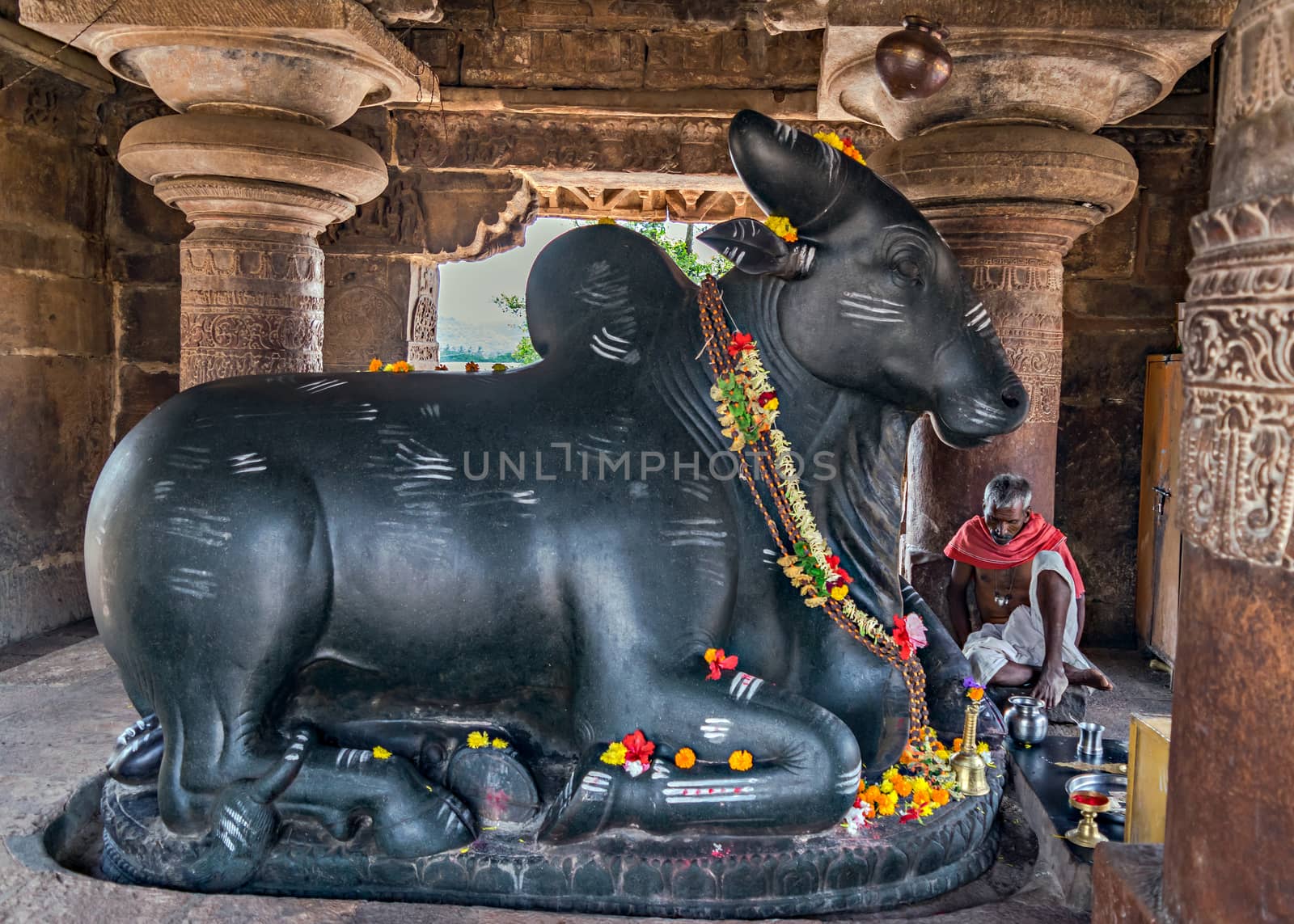 Huge black stone Nandi and priest in shrine near Virupaksha temple. by lalam