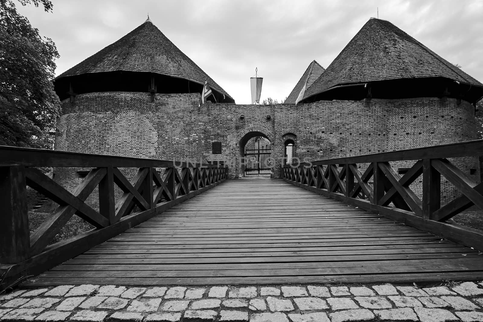 Bridge over the moat and a medieval fortified castle in Miedzyrzecz in Poland, monochrome