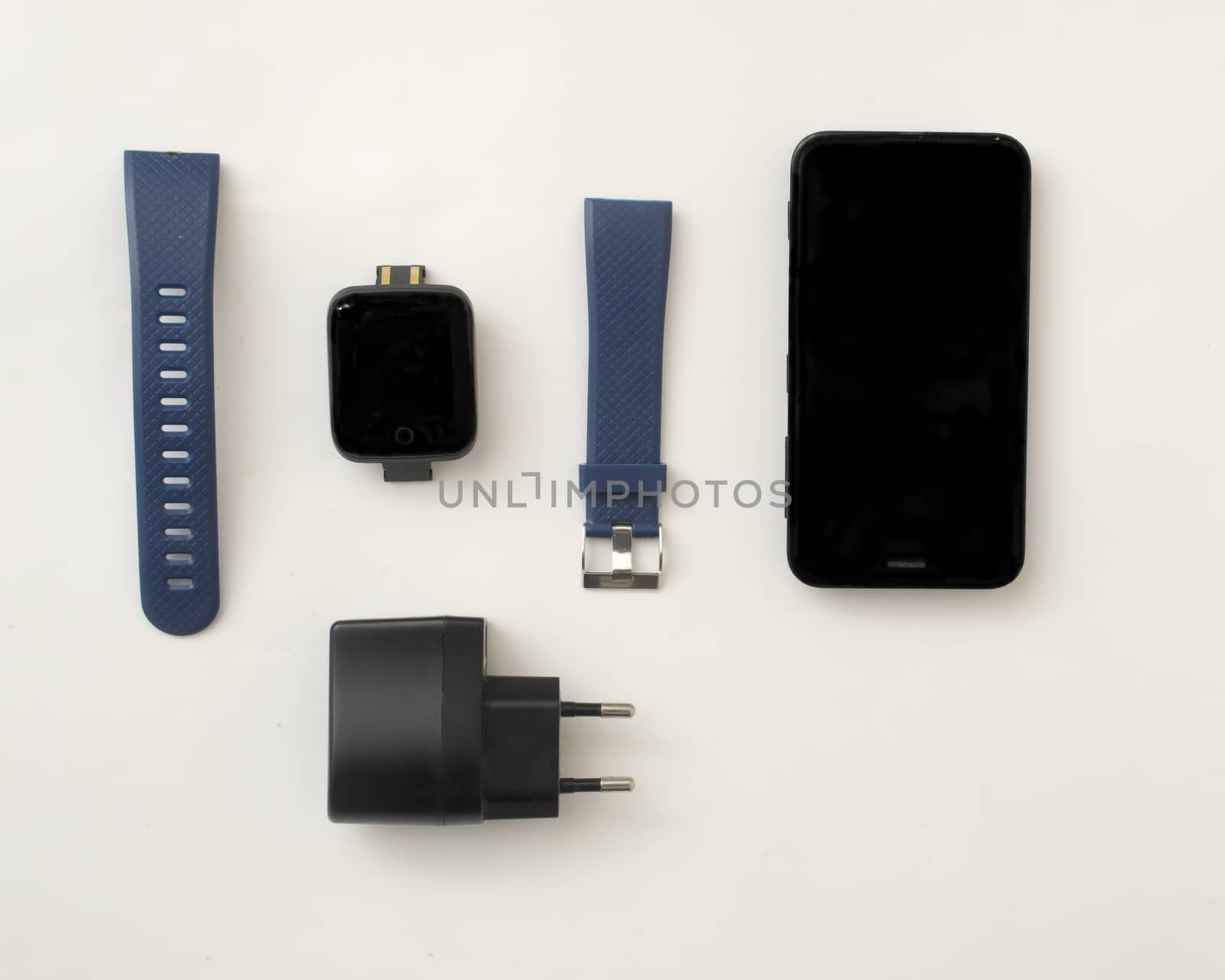 Layout of smart watch accessories.Smart watch, two silicon watchbands,smartphone and charger on white background