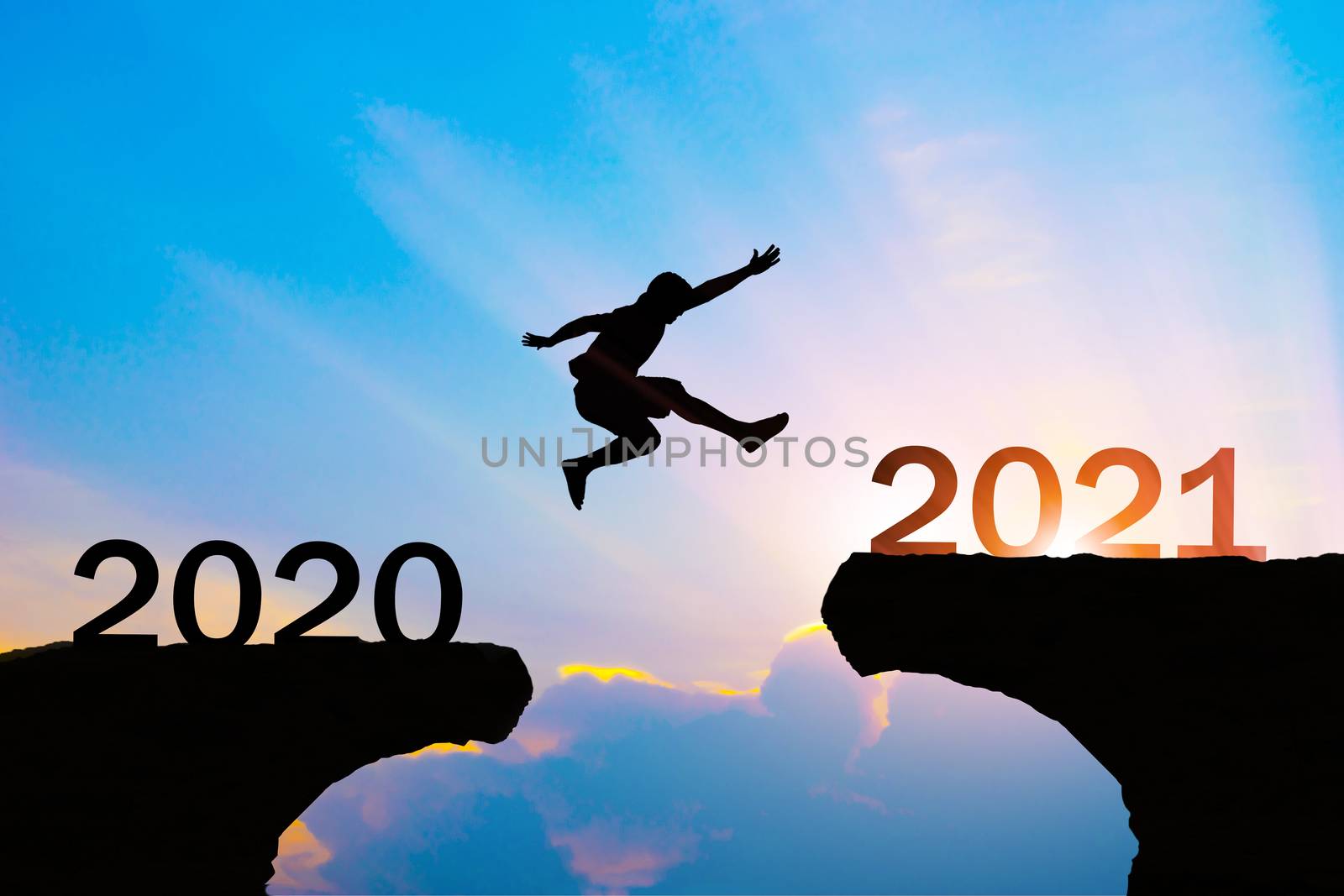 Man jump silhouette between year 2020 and 2021 new year concept. by sompongtom