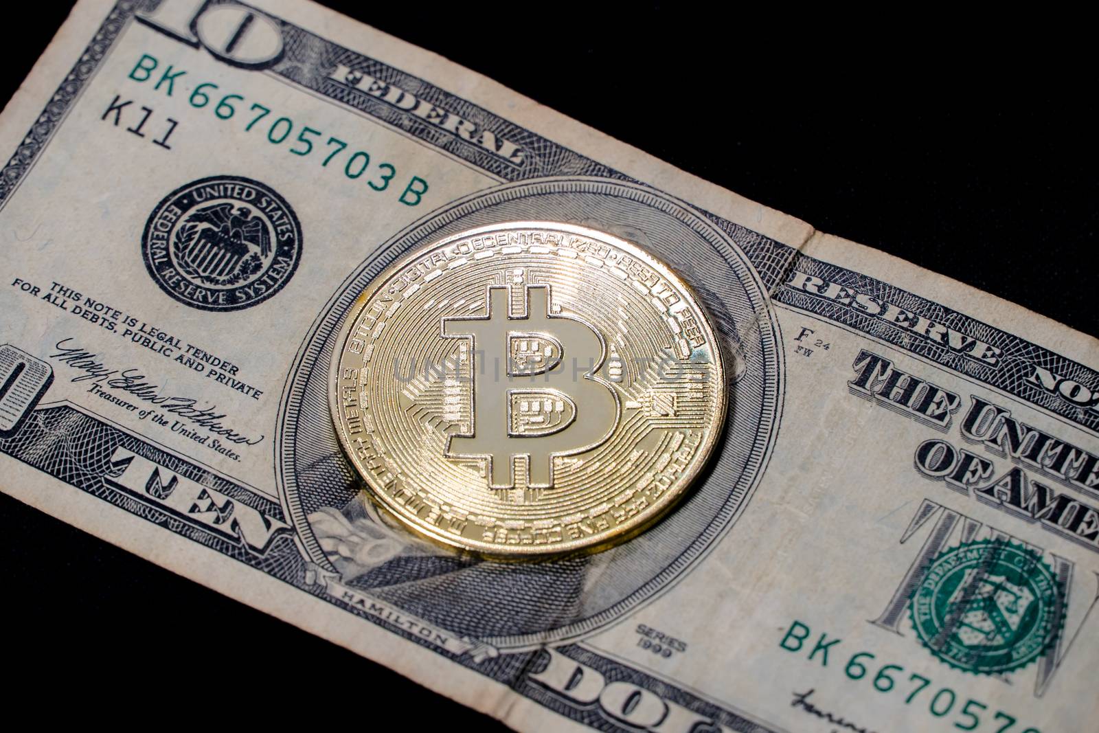 The bitcoin coin lies on a $ 10 bill in close-up. Money and Fina by YevgeniySam