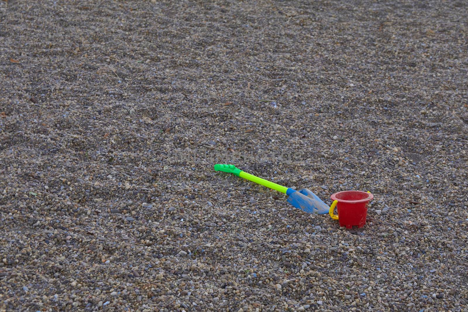 bucket and shovel of children thrown in the stone sand of a park