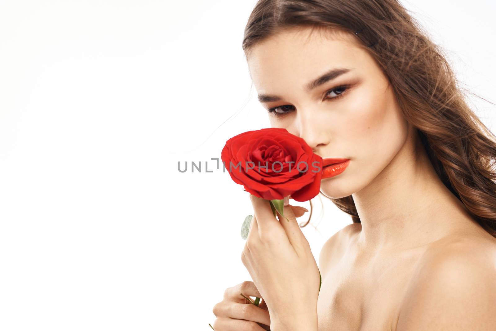 Woman with naked shoulders and red rose evening makeup light background. High quality photo