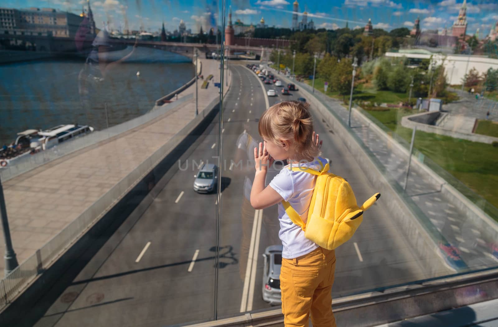 A little girl looks through the glass on a floating bridge in Moscow.