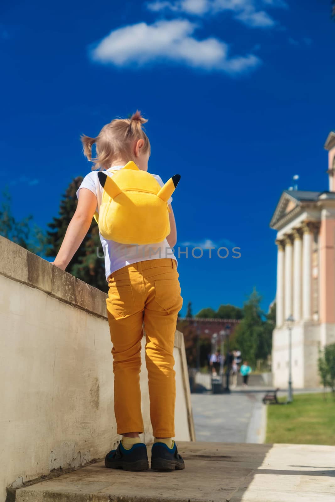 Little girl stands with her back on the porch of the building.