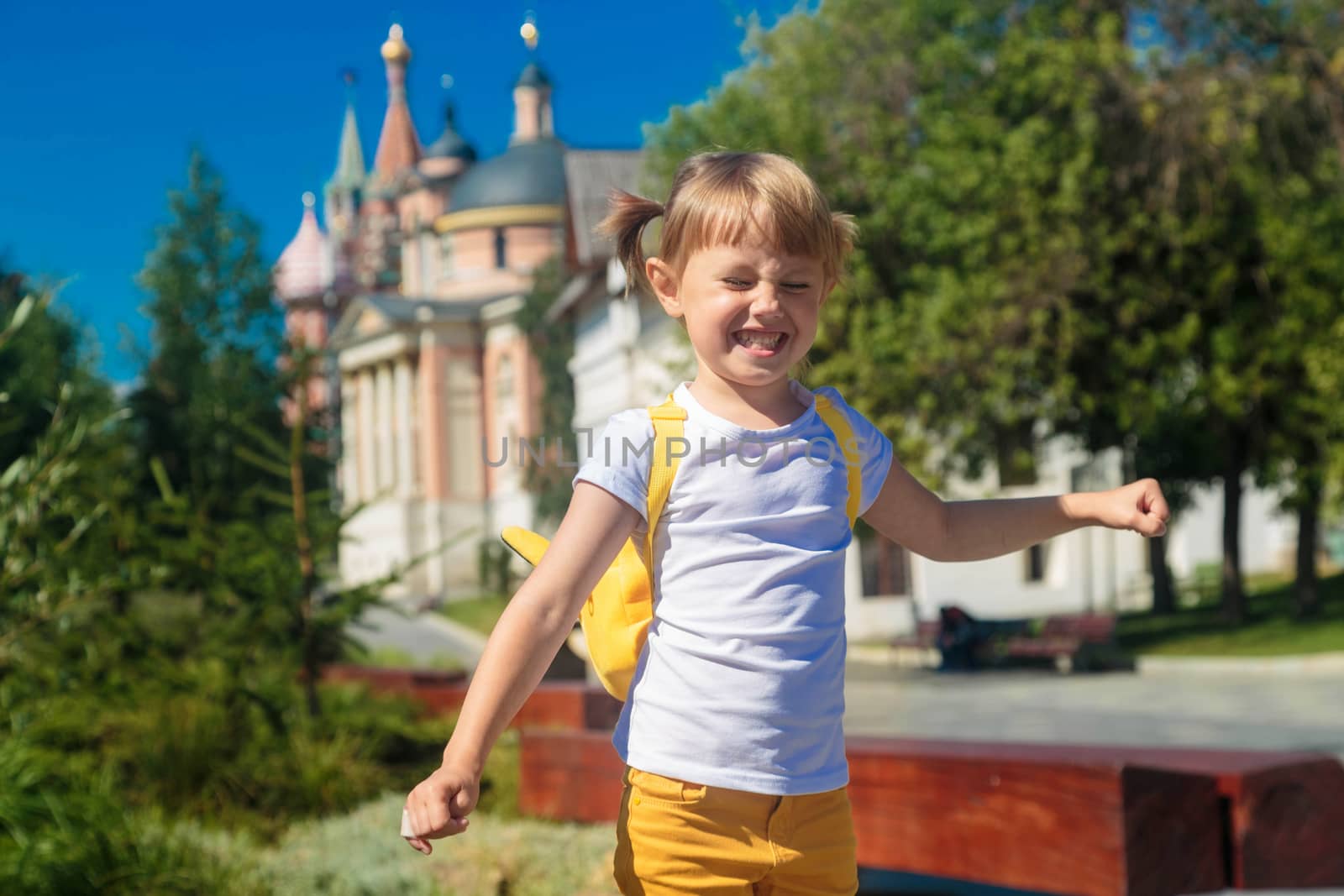 Positive little girl walking on the curb trying to keep her balance.