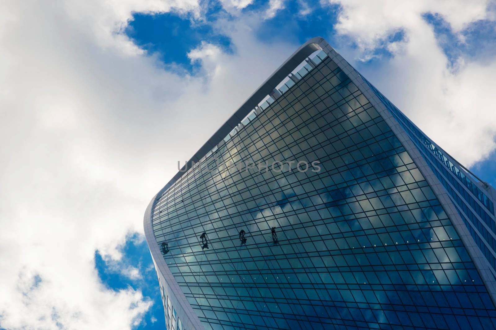 Industrial climbers are washing glass on the facade of a skyscraper. by galinasharapova