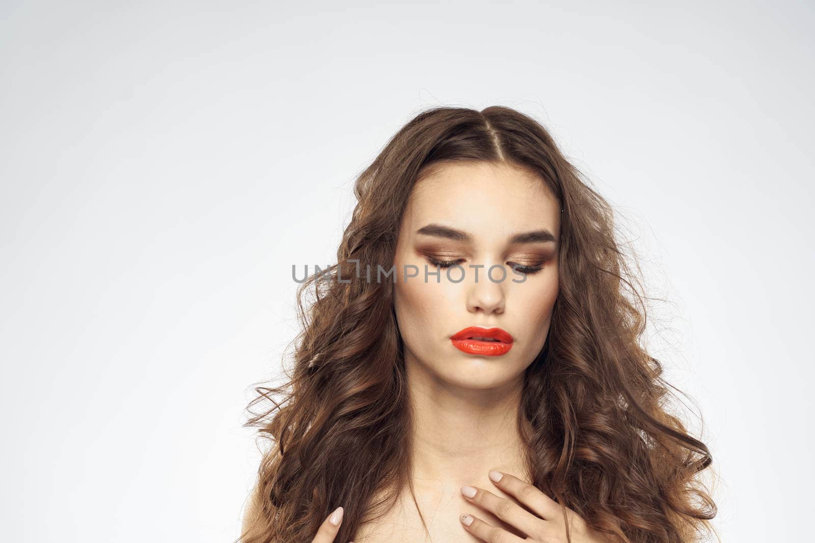 woman with bare shoulders wavy hairstyle glamor makeup light background. High quality photo