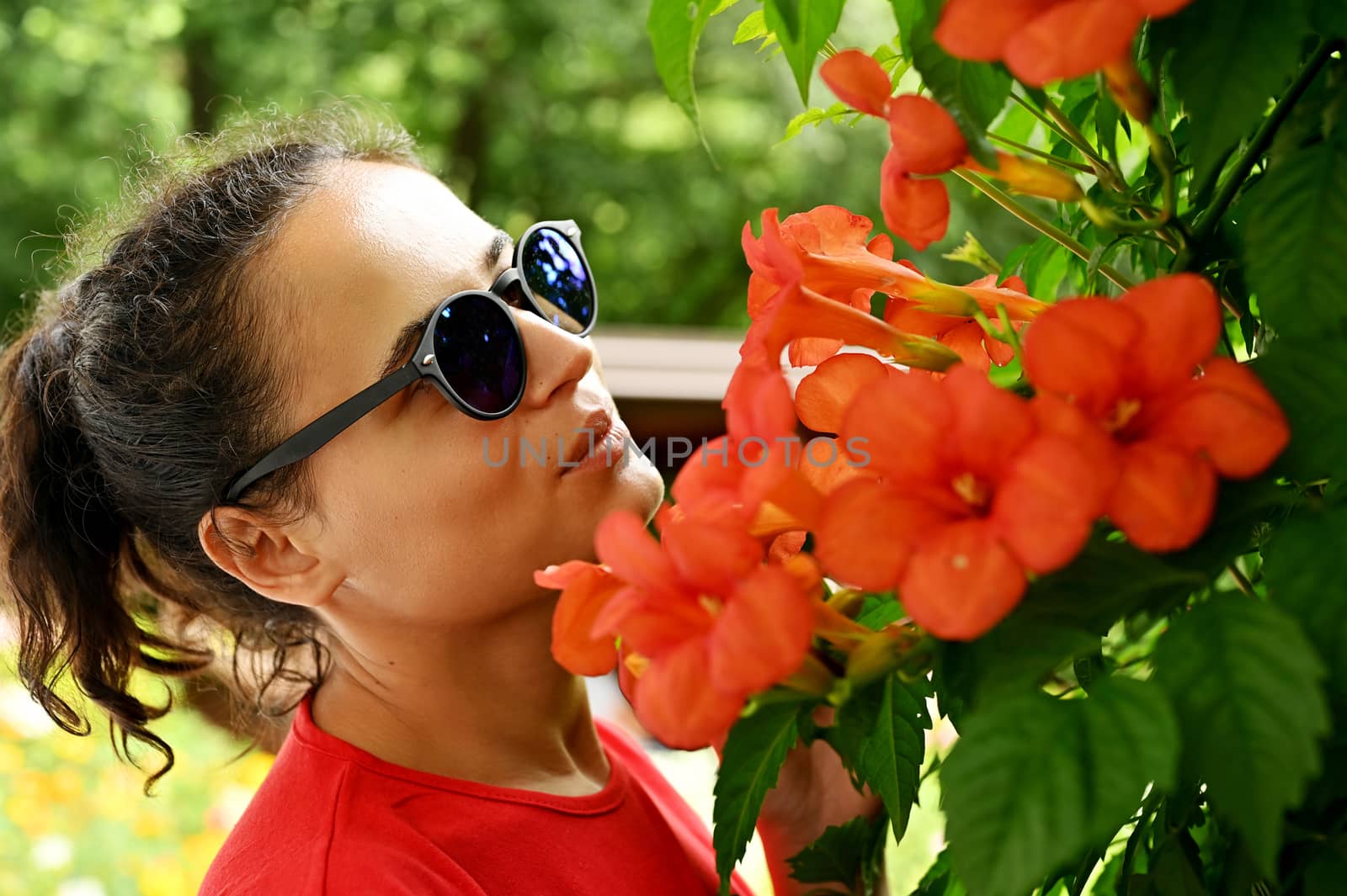 Beautiful young woman smelling red flowers in the park. Sarajevo, Bosnia and Herzegovina