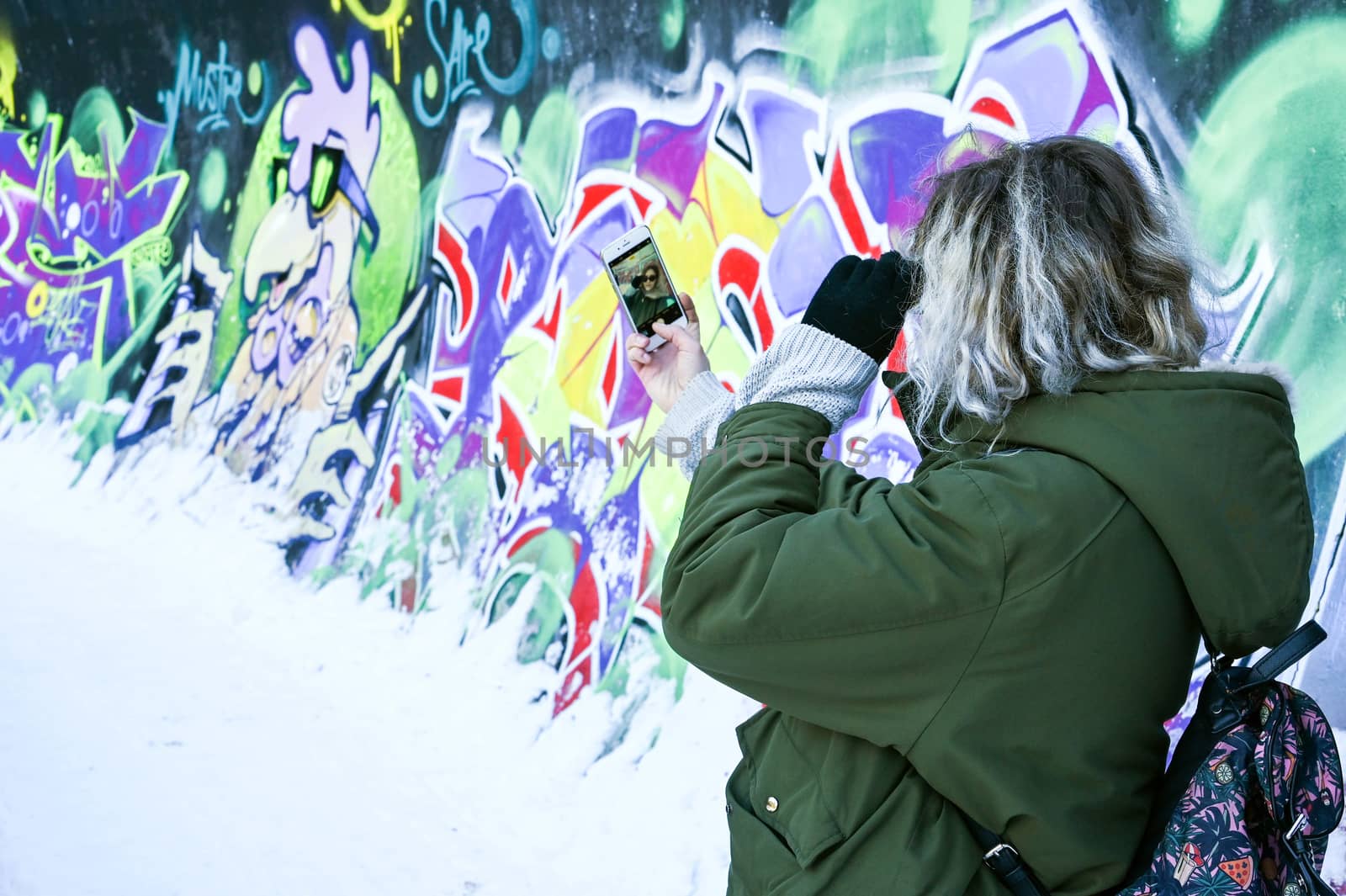 Young pretty girl making selfie on graffiti background