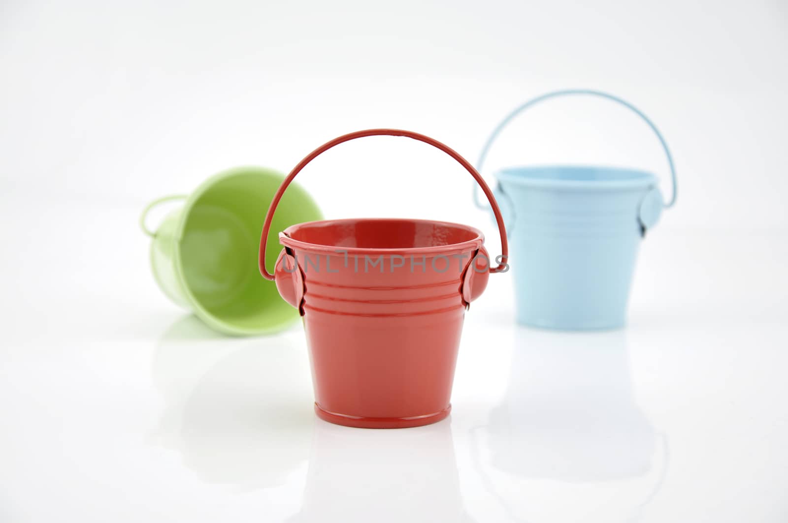 Three metal buckets of different colours with handle, isolated on white background