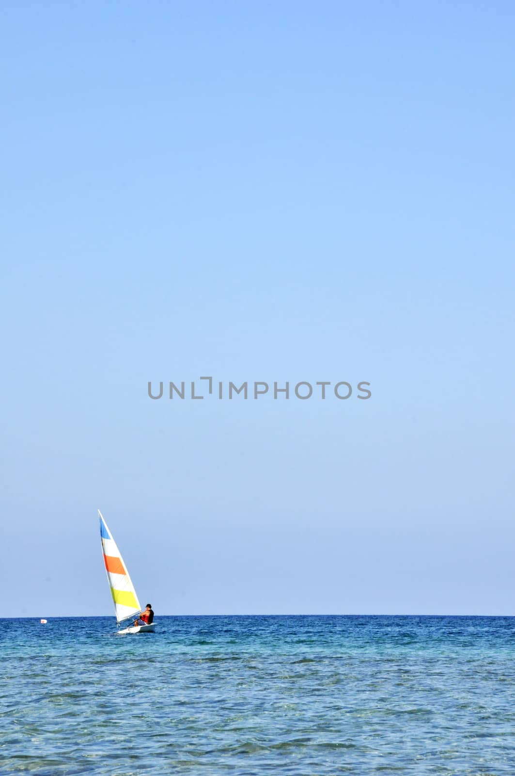 A colorful sailboat with a captain sails the Cyprus Sea during summer vacation