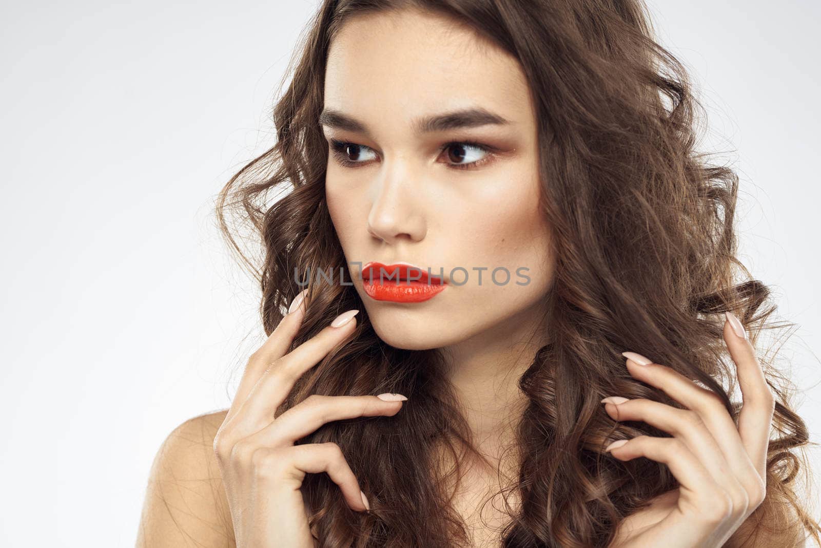woman with bare shoulders wavy hairstyle glamor makeup light background. High quality photo