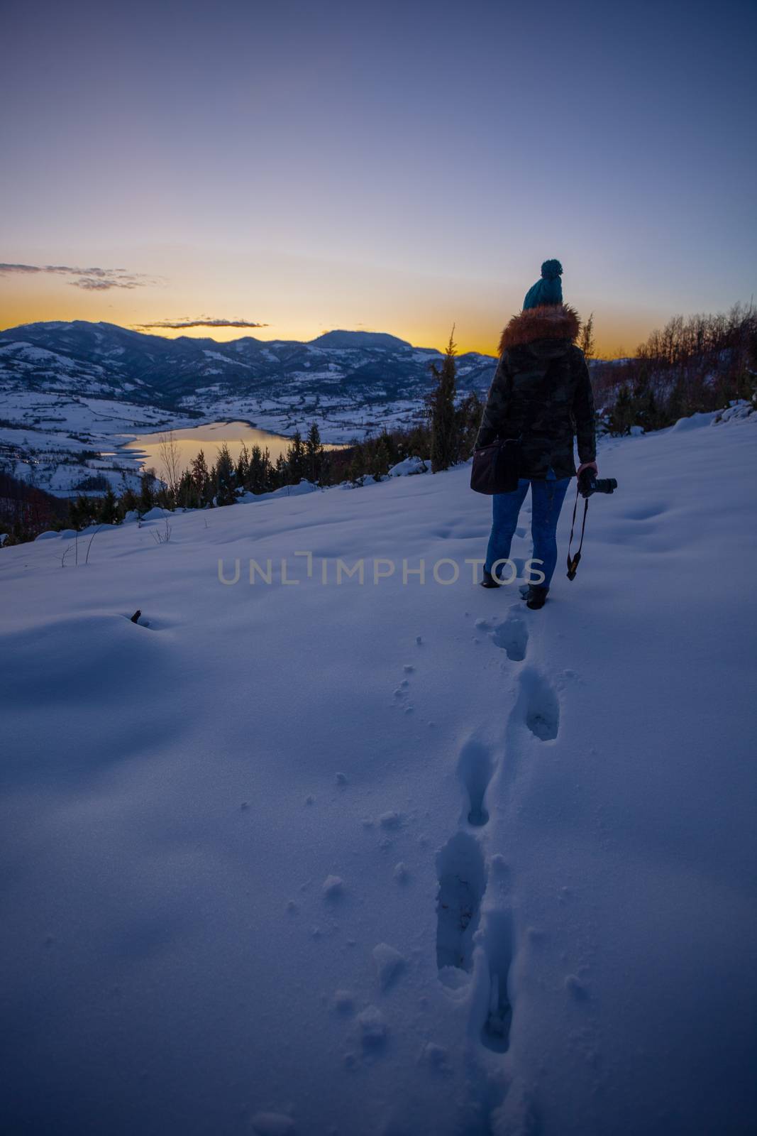 Photographers photographing winter lake mountain scene in sunset, alone in wilderness. Rovni, Valjevo, Serbia