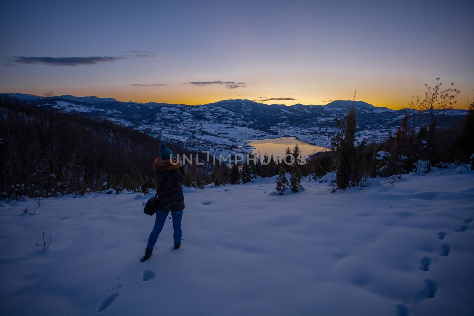 Photographers photographing winter lake mountain scene in sunset by adamr