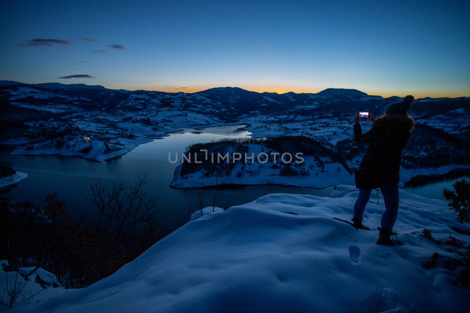 Photographers photographing winter lake mountain scene in sunset, alone in wilderness. Rovni, Valjevo, Serbia