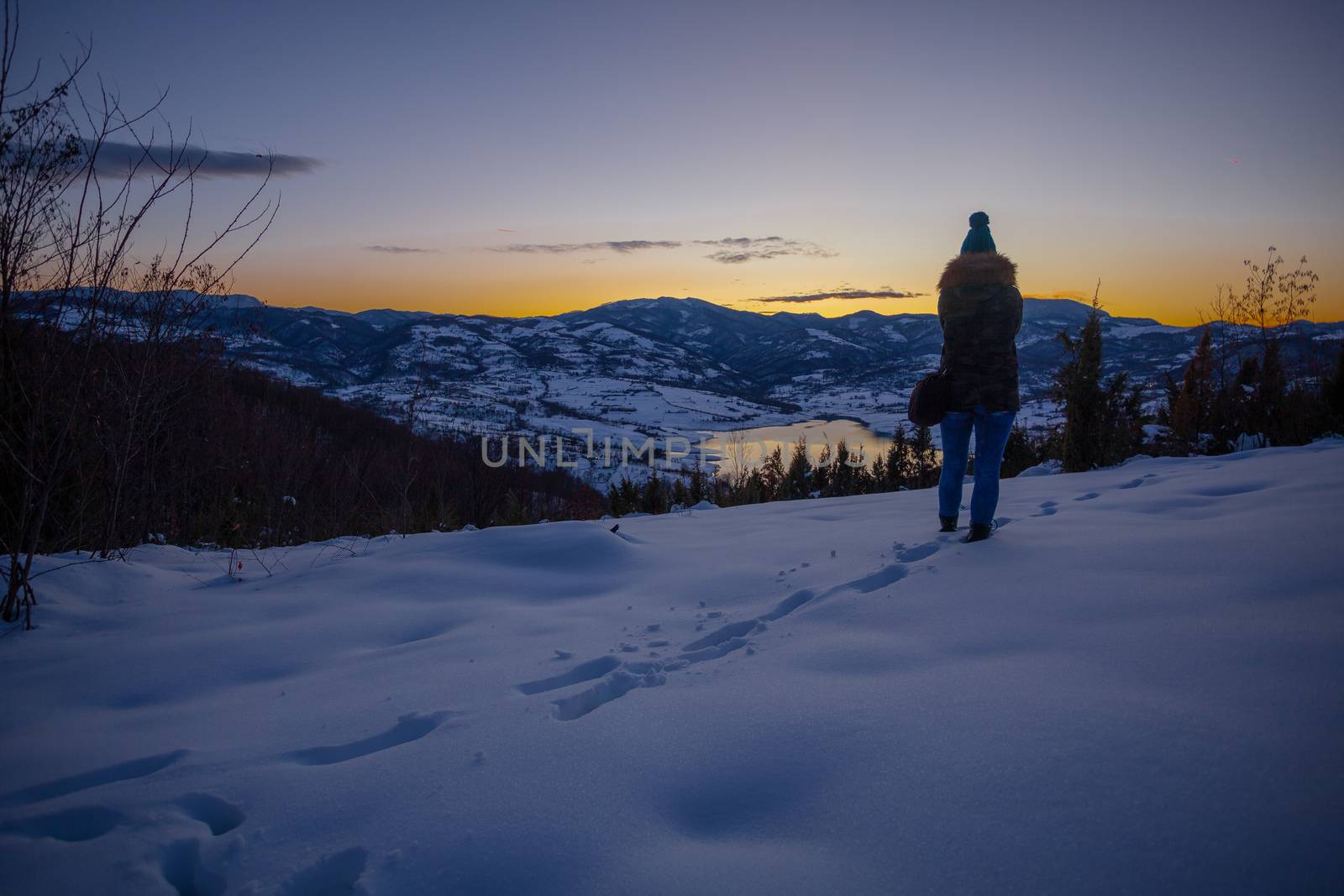 Photographers photographing winter lake mountain scene in sunset, alone in wilderness. Rovni, Valjevo, Serbia