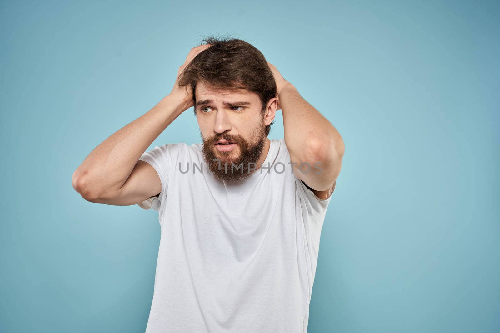 Man in white t-shirt emotions facial expression cropped view studio blue background lifestyle. High quality photo
