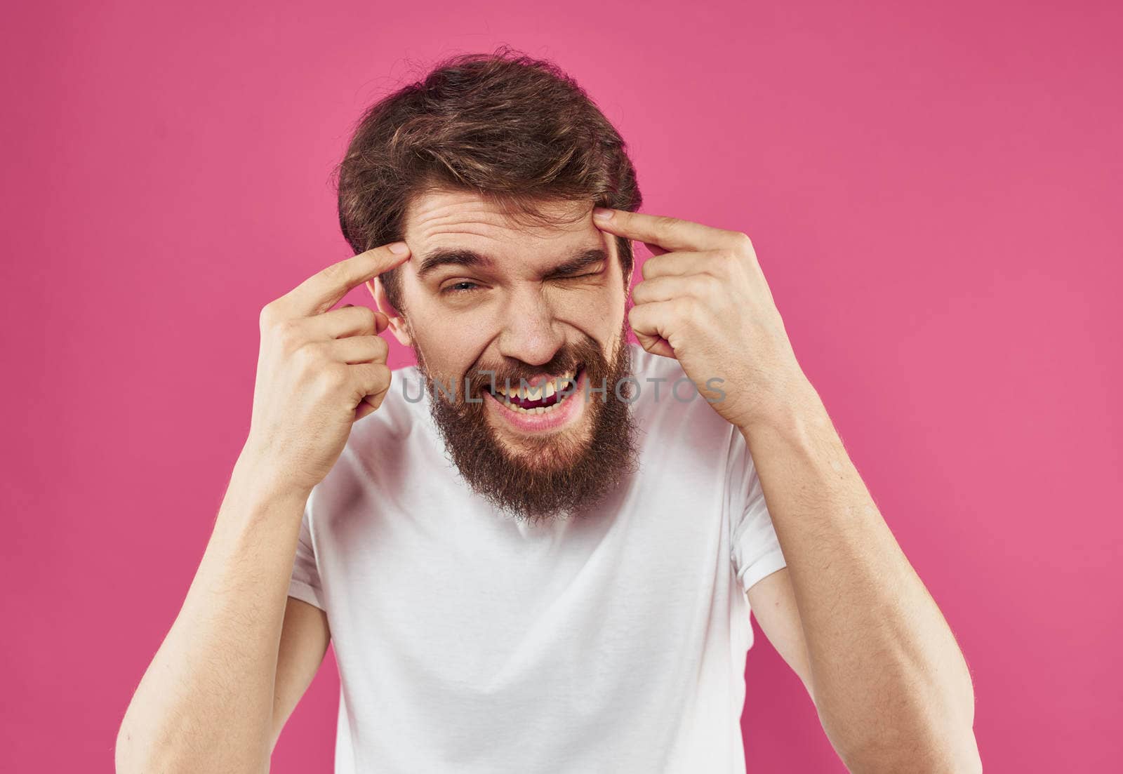 Happy man holds his hands near his face and laughs on a pink background. High quality photo