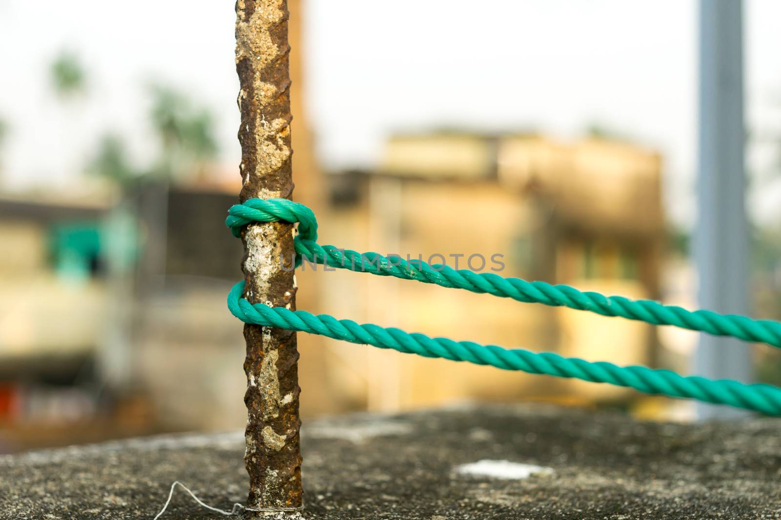 A rope is tied in a knot around a fence post, rope tied Hitch Knots on a rusty iron pole isolated from background. by sudiptabhowmick