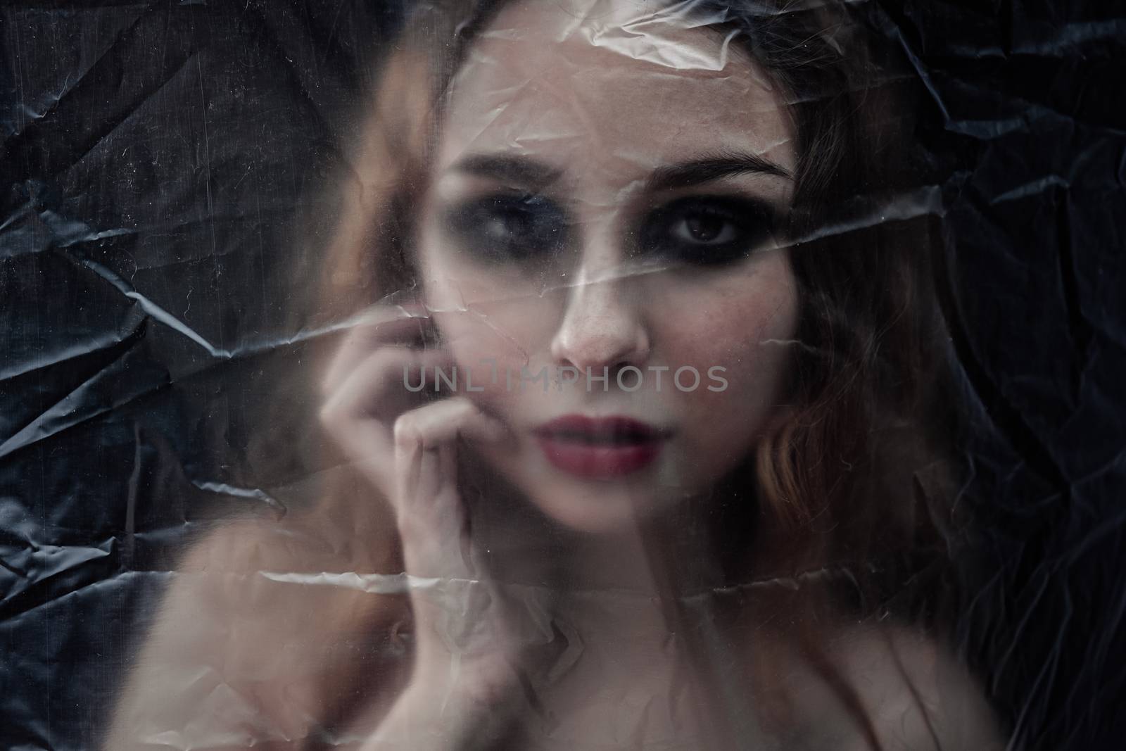 Young beauty sad woman trapped behind a plastic sheet as protect by snep_photo