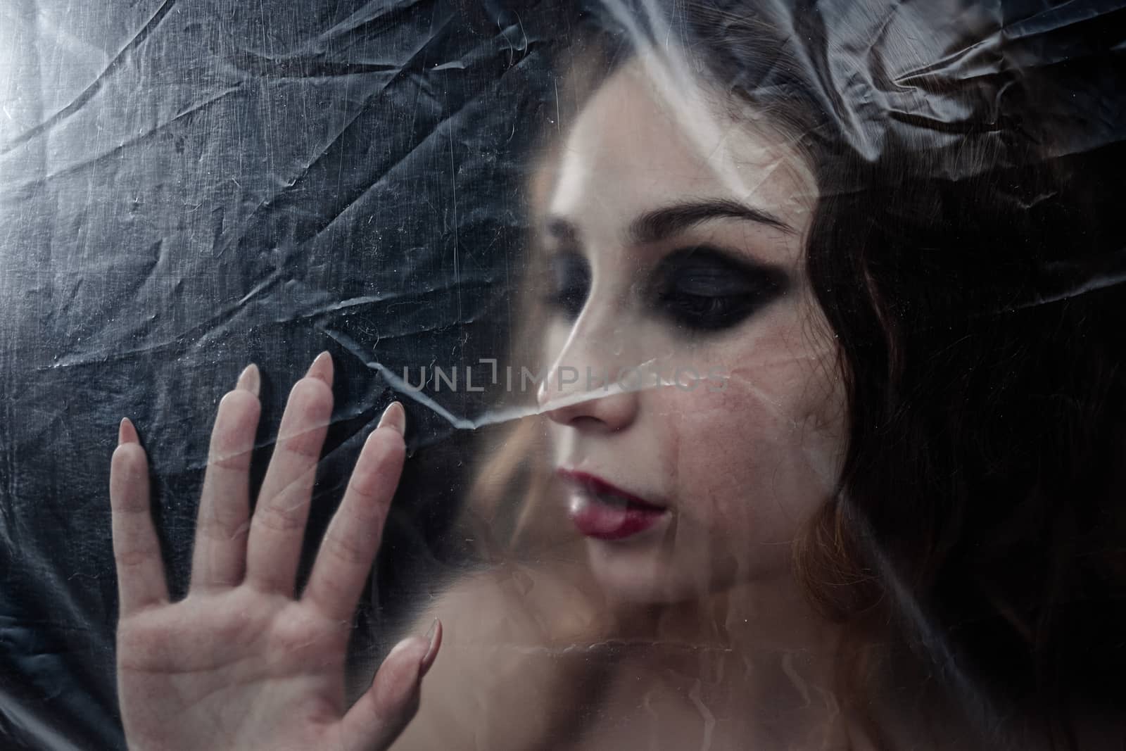 Young beauty sad woman trapped behind a plastic sheet as protect by snep_photo
