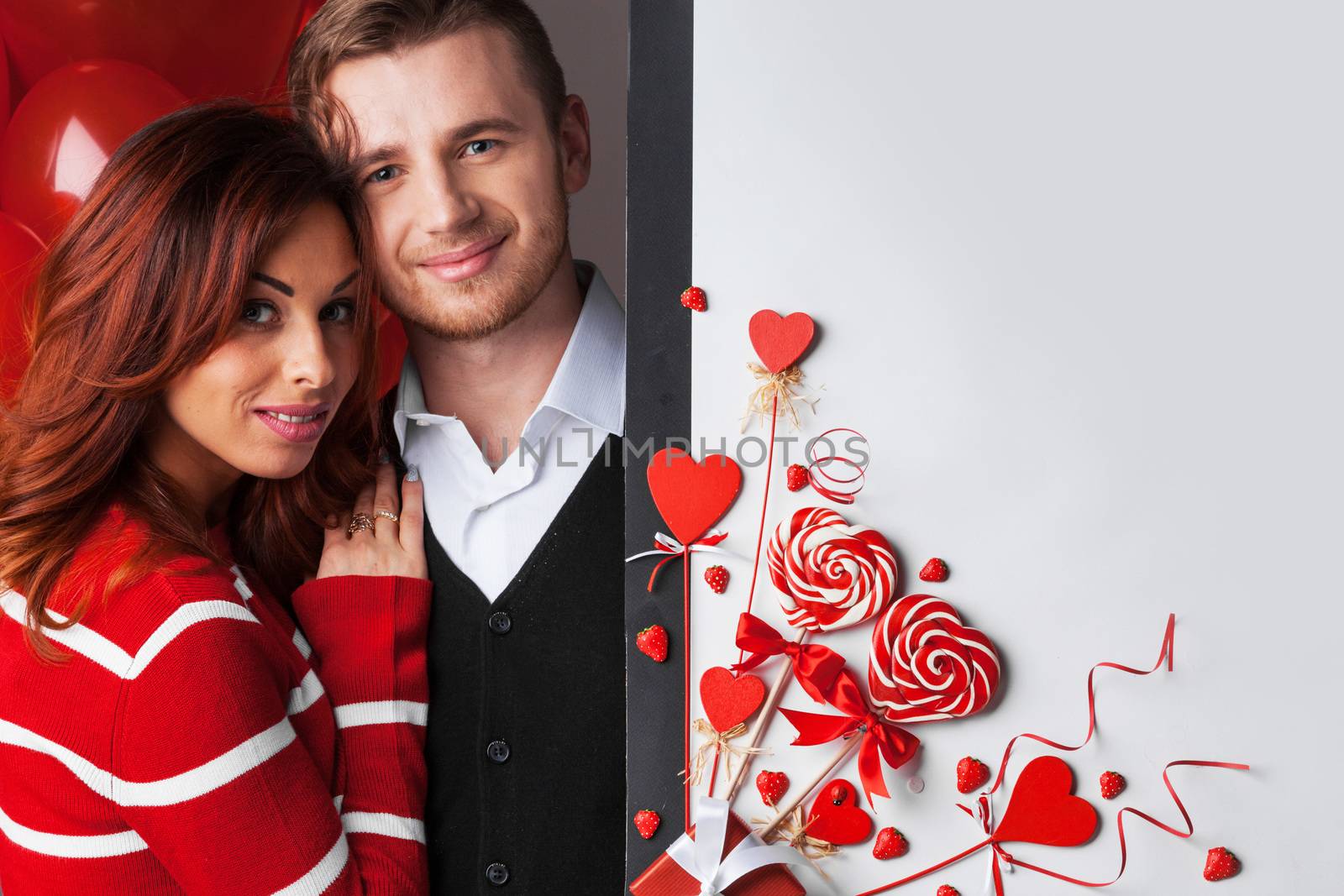 Happy young couple with heart shaped red decoration on white background with copy space for text. Valentine's day celebration