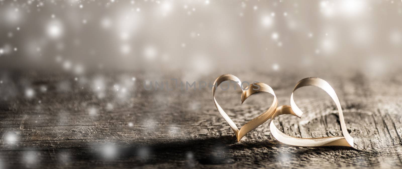 Two golden ribbon hearts on wooden background with copy space for text, Valentines day concept