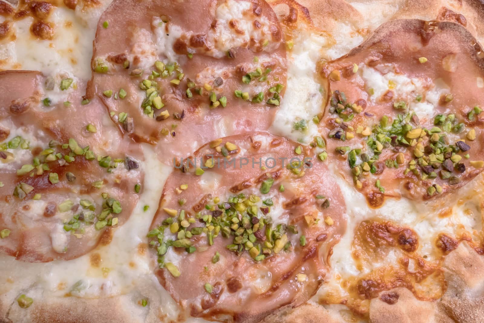 Gourmet pizza with mortadella, pistachio grains and mozzarella.