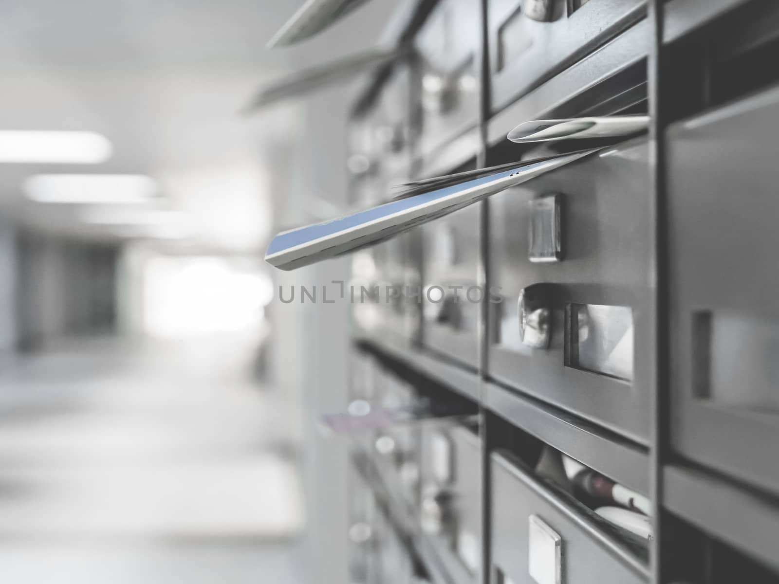 Mailboxes in the condominium. Mailboxes filled. Mail boxes filled of leaflets and letters. Defocused blurry background.