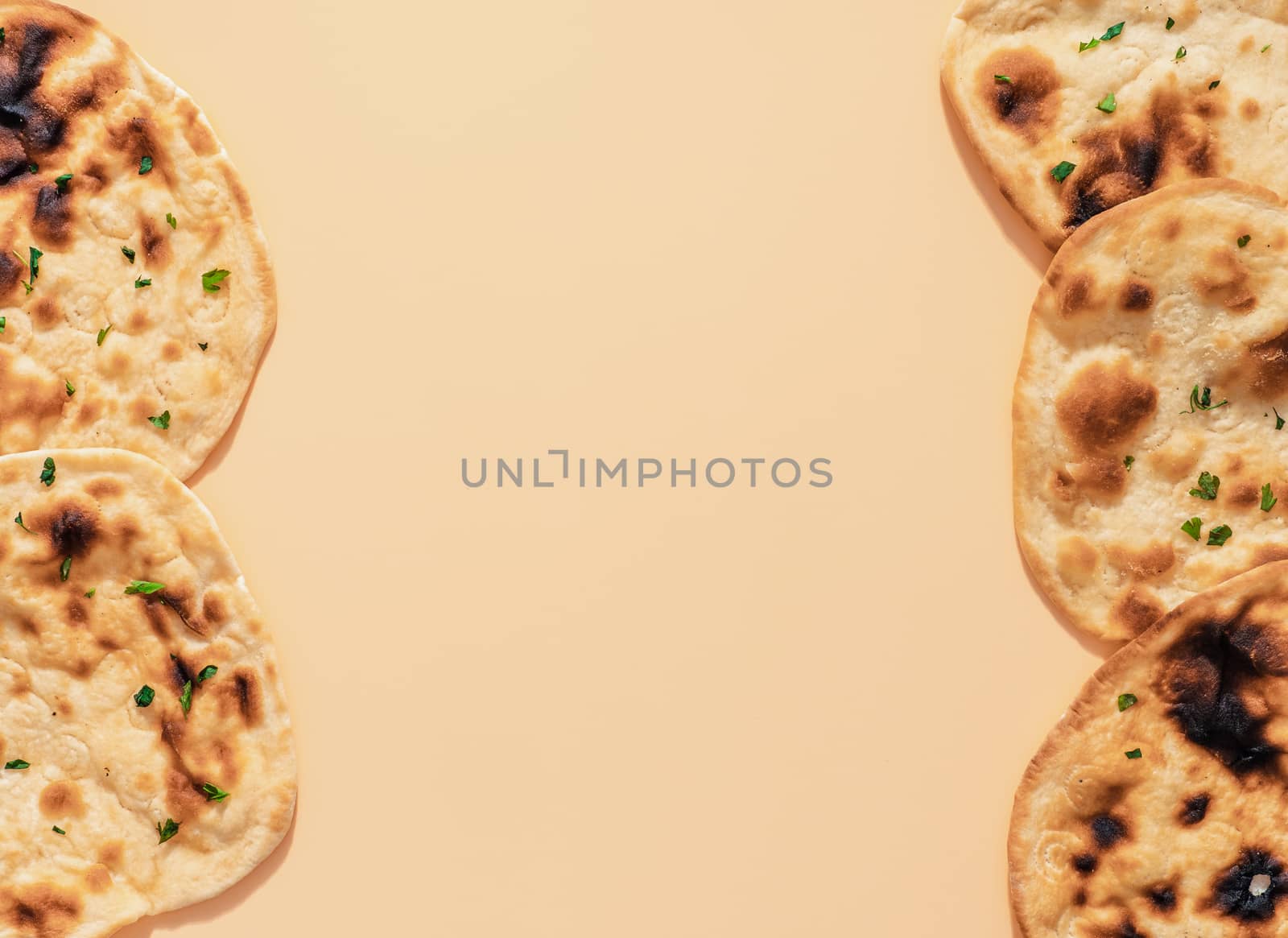 Pattern of fesh naan bread on yellow cream background with copy space in center. Top view of perfect naan flatbreads as indian pakistani food background