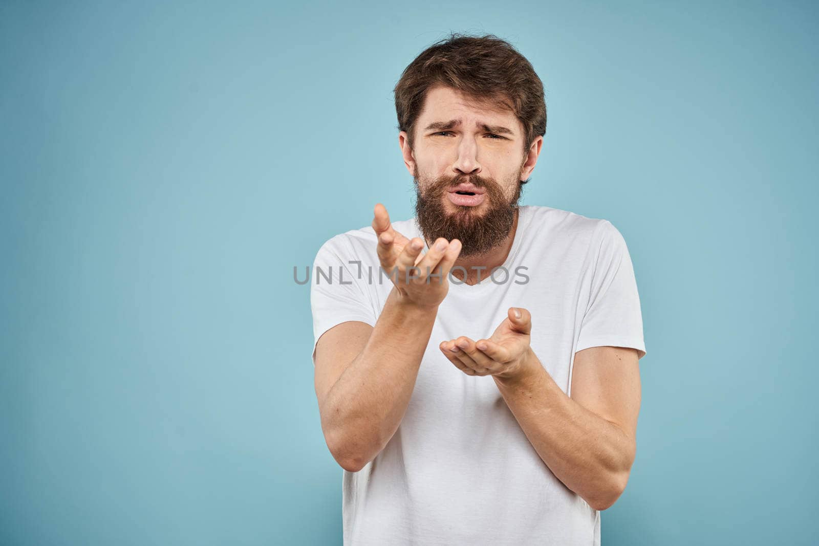 Man in white t-shirt emotions facial expression cropped view studio blue background lifestyle. High quality photo