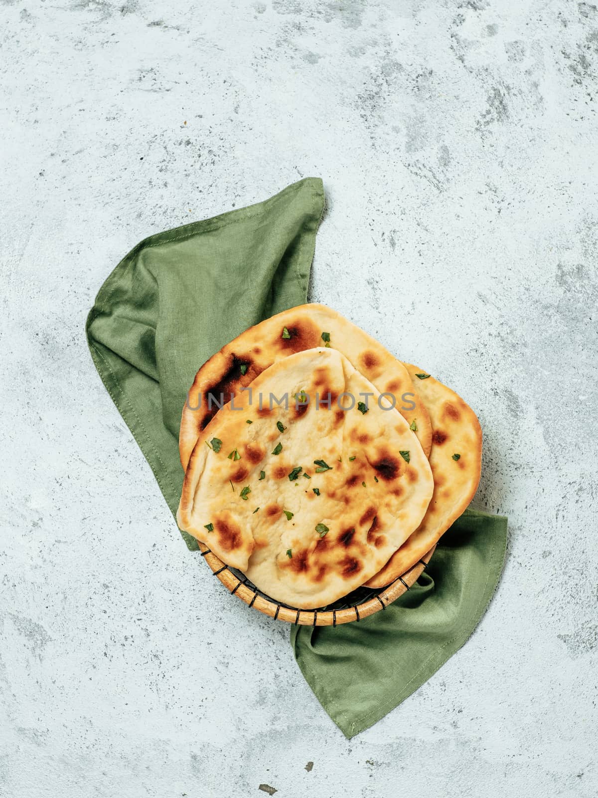 Fresh naan bread on gray cement background with copy space. Top view of several perfect naan flatbreads. Vertical