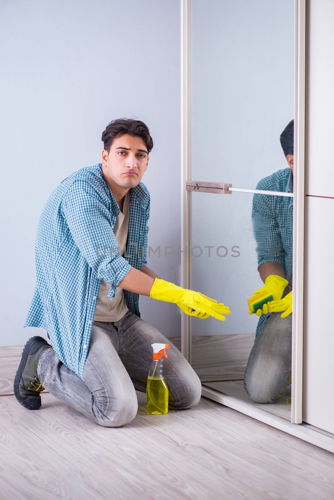 Young man cleaning mirror at home hotel
