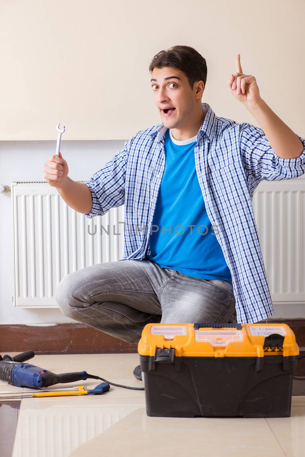Young repairman contractor repairing heating panel 