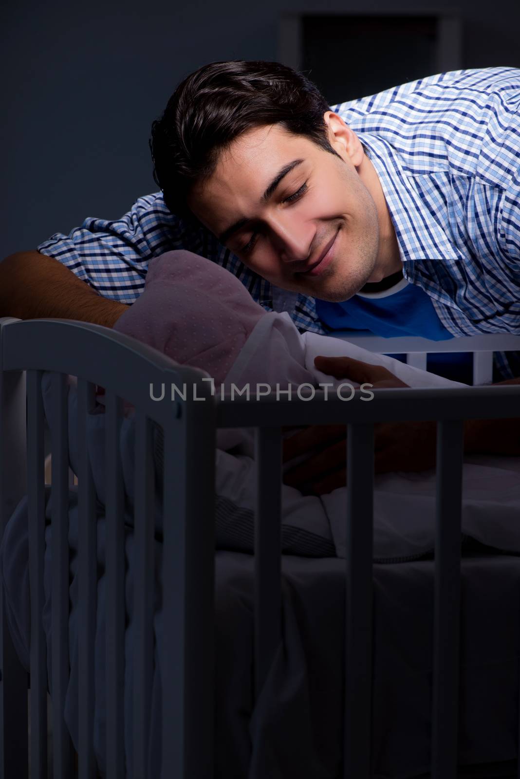 Happy dad looking after newborn baby at night
