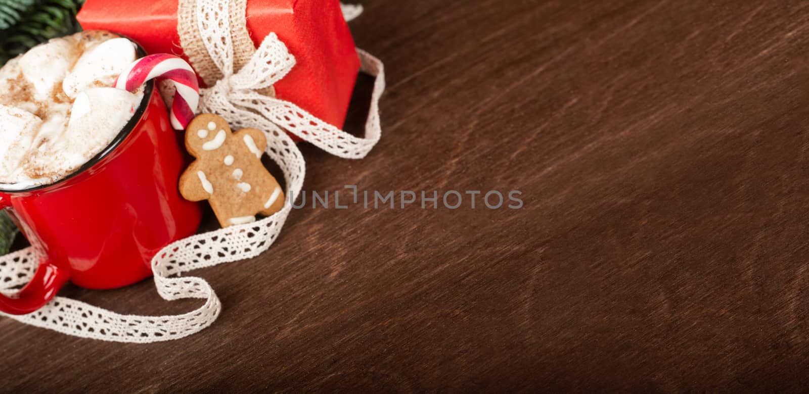 Cocoa in red mug with marshmallows and candy cane and Christmas fir tree on dark wooden background