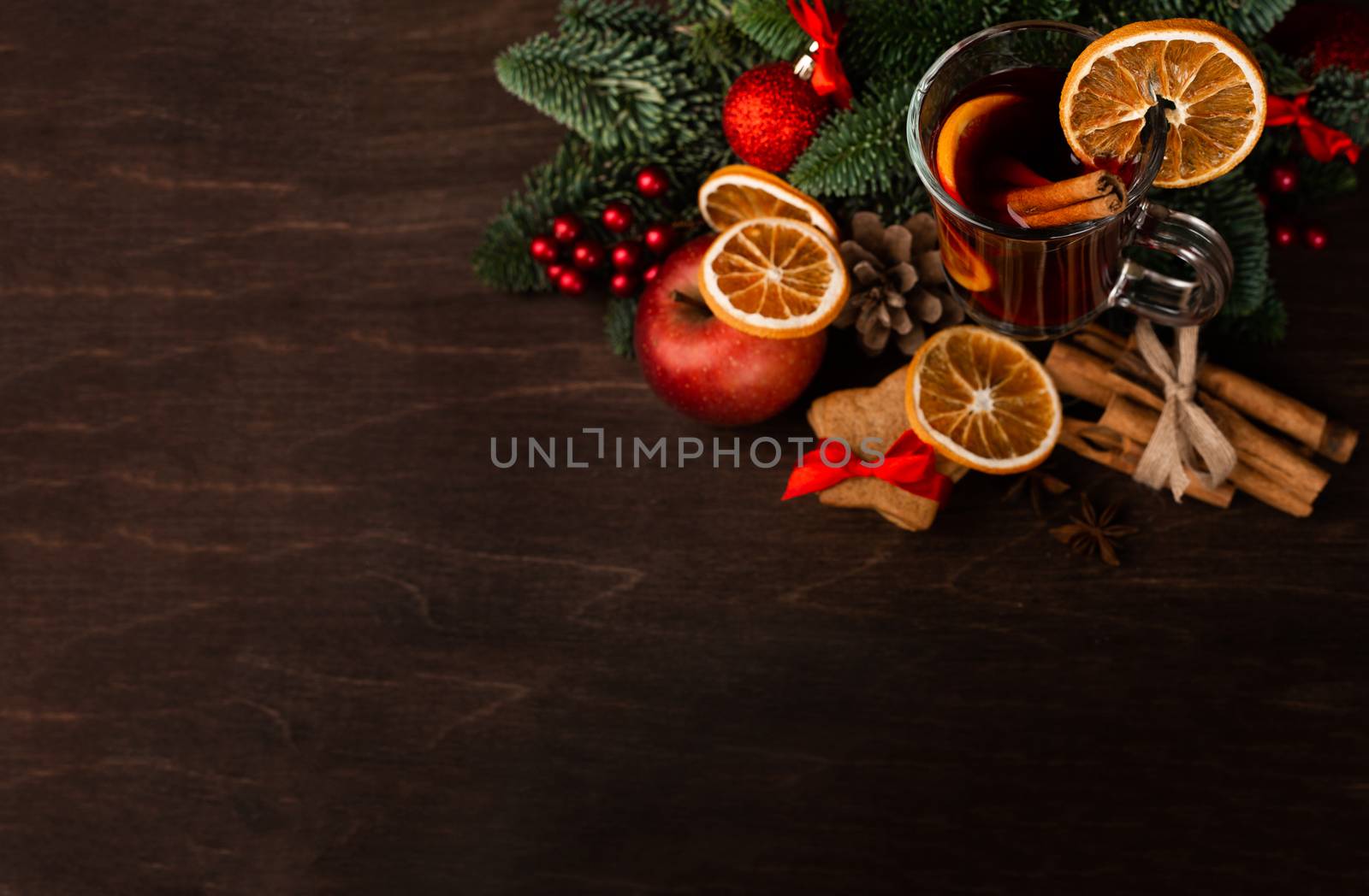 Mulled wine with cinnamon sticks orange fir tree branch and baubles Christmas composition over dark wooden background
